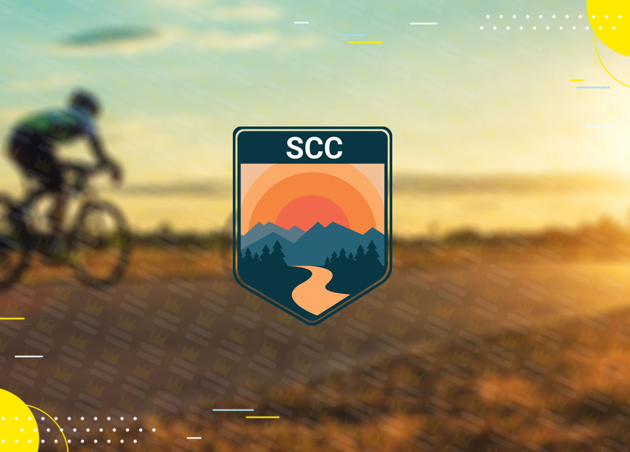 The scc logo with a person riding a bike on the road.
